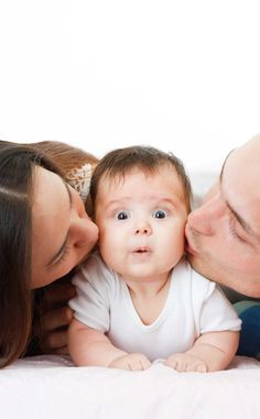 a man and woman kissing a baby on the forehead