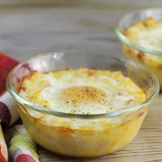 two glass bowls filled with food on top of a wooden table