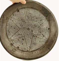 a person holding a metal strainer in their left hand, with holes on it