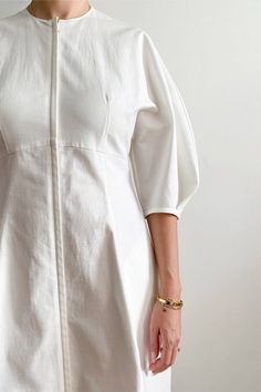 a woman wearing a white dress and gold bracelets