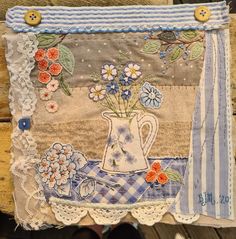 a piece of fabric with flowers in a vase on top of a blue and white checkered table cloth