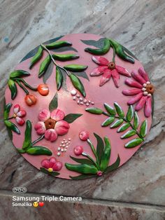 a pink plate with flowers and leaves painted on the side, sitting on a marble surface