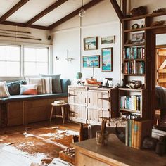 a living room filled with furniture and lots of books on top of a wooden floor