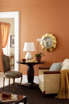 a living room with an orange wall and white trim on the walls, two chairs in front of a coffee table