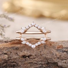 a stack of rings with pearls on top of each other in front of a piece of wood