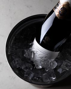 a bottle of champagne sitting on top of an ice bucket filled with chunks of ice