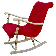 a wooden rocking chair with red fabric and white trimmings on the back, in front of a white background