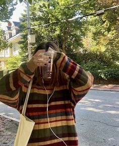 a woman taking a selfie with her cell phone and headphones in the street