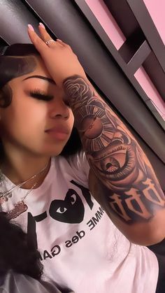 a woman with tattoos on her arm leaning against a wall