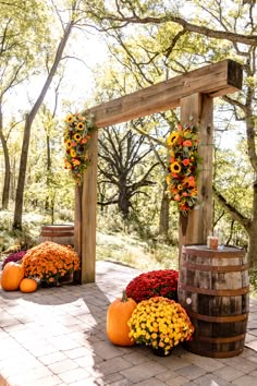 an outdoor ceremony with sunflowers, pumpkins and flowers on the ground next to barrels