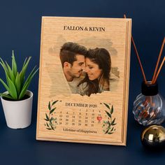 a wooden calendar with an image of a couple on it next to a potted plant