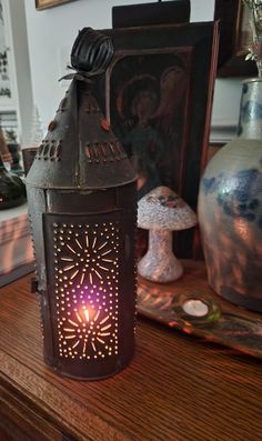 a lit candle sitting on top of a wooden table next to vases and other items