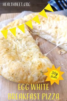 an egg white breakfast pizza on a cutting board with a slice cut out and yellow bunting