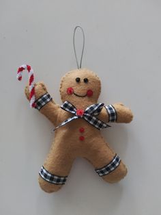 a gingerbread man ornament hanging on a wall with a candy cane in his hand