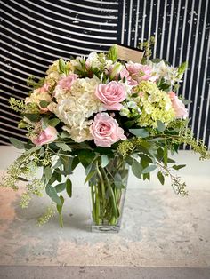 a vase filled with pink and white flowers on top of a marble counter next to a striped wall