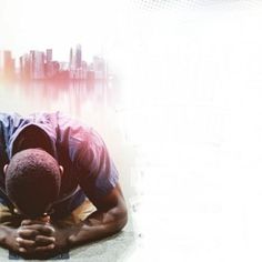 a man laying on the ground in front of a cityscape with his head down