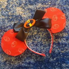 a red mickey mouse ears with black ribbon and an orange pumpkin on it's head