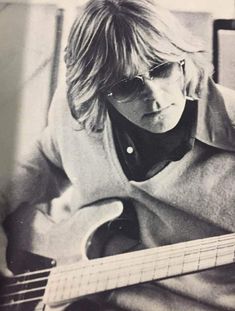 an old black and white photo of a woman with glasses holding a guitar in her hands