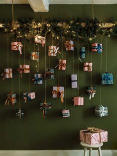 presents are hung on the wall with lights and garlands around them, as well as hanging from strings