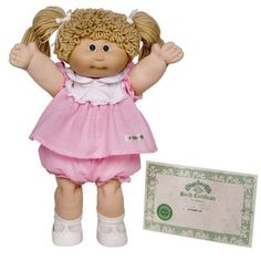 a doll with blonde hair standing next to a certificate