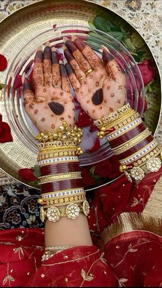 two hands with bracelets and rings on top of a metal platter filled with flowers