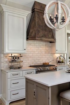 a kitchen with white cabinets and a chandelier hanging from the ceiling over the island