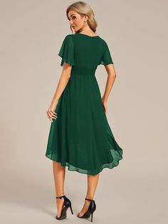 a woman is wearing a green dress with short sleeves and high heeled heels on her feet