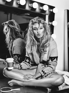 a black and white photo of a woman sitting in front of a mirror with her legs crossed