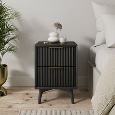 a black nightstand with two drawers next to a bed and potted plant on the side