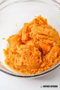 a glass bowl filled with mashed carrots on top of a white countertop