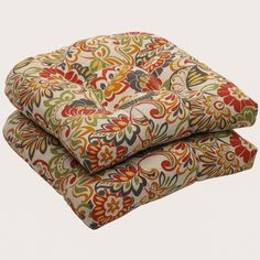 two cushions are stacked on top of each other, one has an orange and green floral pattern