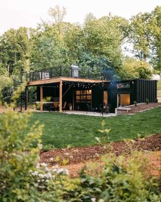 a black building sitting in the middle of a lush green field with lots of trees