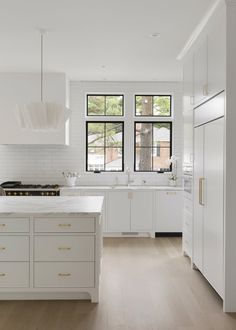 a large kitchen with white cabinets and wood flooring, along with an island in the middle