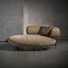 a couch that is sitting in the middle of a room with concrete walls behind it