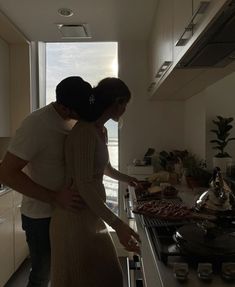 a man and woman standing in front of a stove top oven next to each other