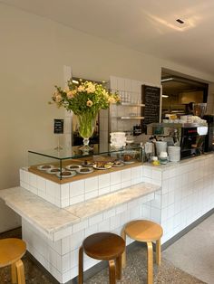 a counter with two stools in front of it and a flower vase on top