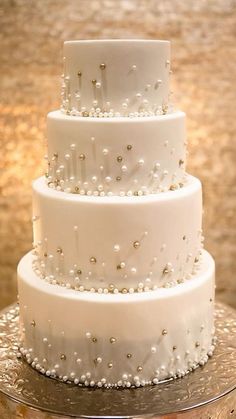 a three tiered white cake sitting on top of a table next to lit candles