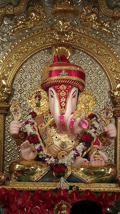 the statue of lord ganesha is surrounded by red and gold decorations