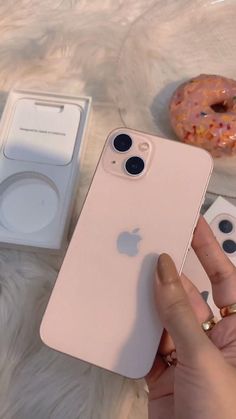 a person holding an iphone in their hand next to two donuts and a doughnut