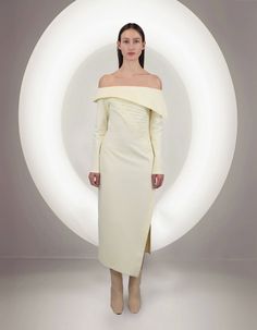 a woman is standing in front of a white circle wearing an off the shoulder dress