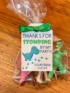 there is a plastic bag with some toy dinosaurs in it on the table next to a sign that says, thanks for stomping by my party your friend lucas