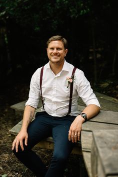 a man wearing suspenders and a white shirt is sitting on a bench