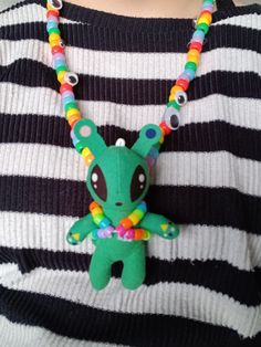 a person wearing a striped shirt with a green toy on it's chest and colorful beads around the neck