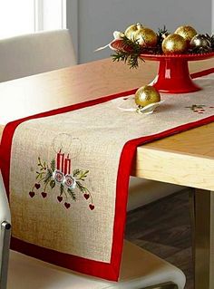 a red and white table runner with ornaments on it sitting on a dining room table