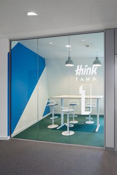 an office with glass walls and white chairs in front of the window that reads think think