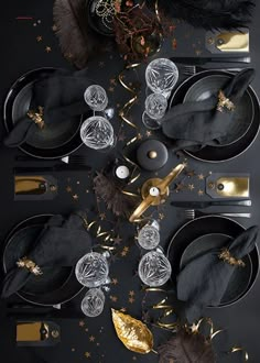 black and gold table setting with silverware, napkins, and other items on it