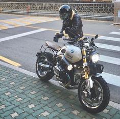 a man in black leather jacket sitting on a motorcycle with helmet and gloves over his face