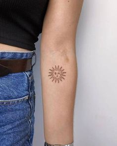 a woman's arm with a small sun tattoo on the left side of her arm