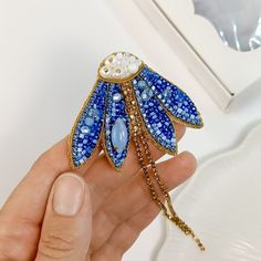 a person holding a blue and white brooch in their hand