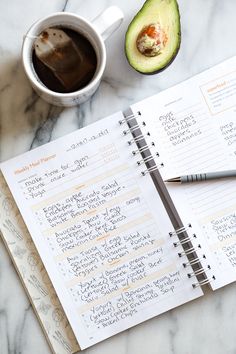 an avocado next to a cup of coffee on top of a white marble table